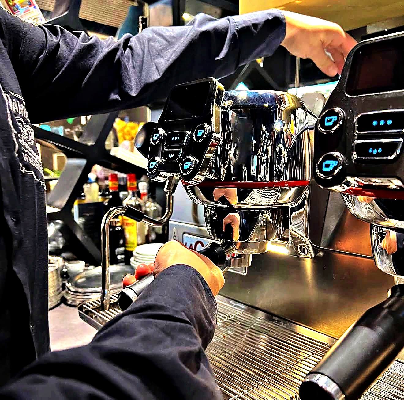Barista spannt den Siebträger in die Espressomaschine ein