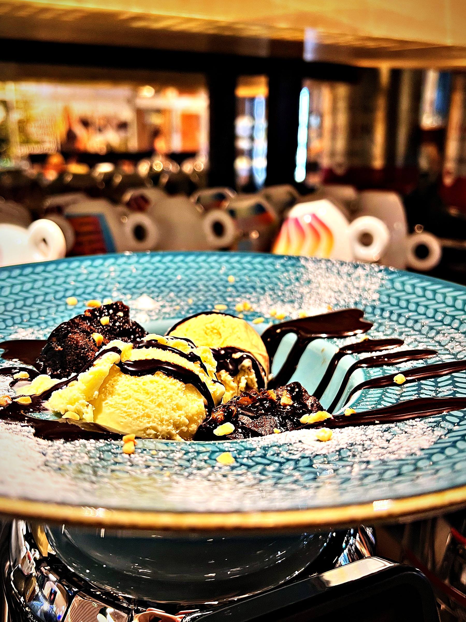 Warmer Brownie mit Vanilleeis und Schokoladensauce auf einem türkisen Teller