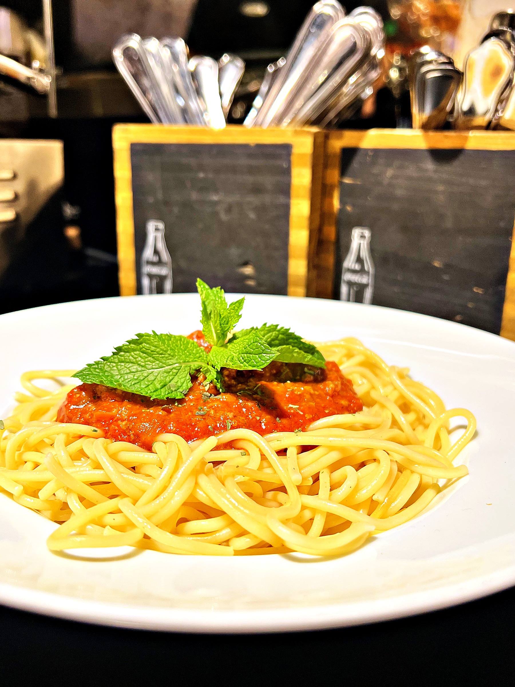 Spaghetti Bolognese mit einem Minzzweig auf einem weißen Teller