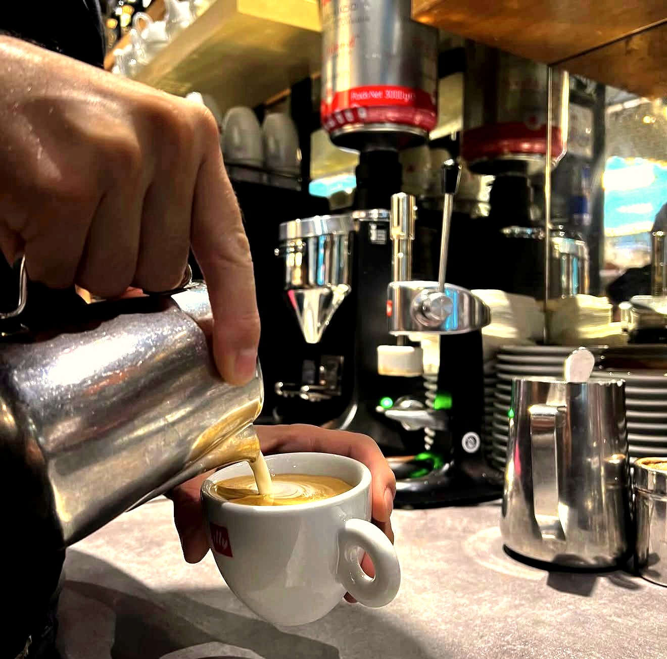 Barista pouring milk into an illy cup at daylounge