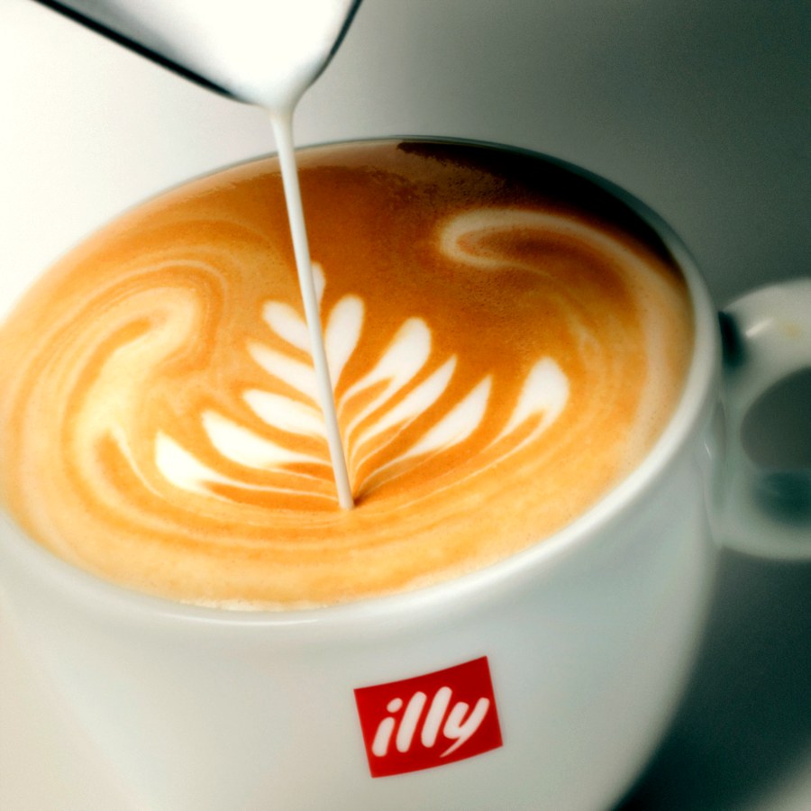 Latte art being poured into an illy coffee cup